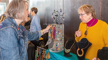 Customer talks with jewelry artisan