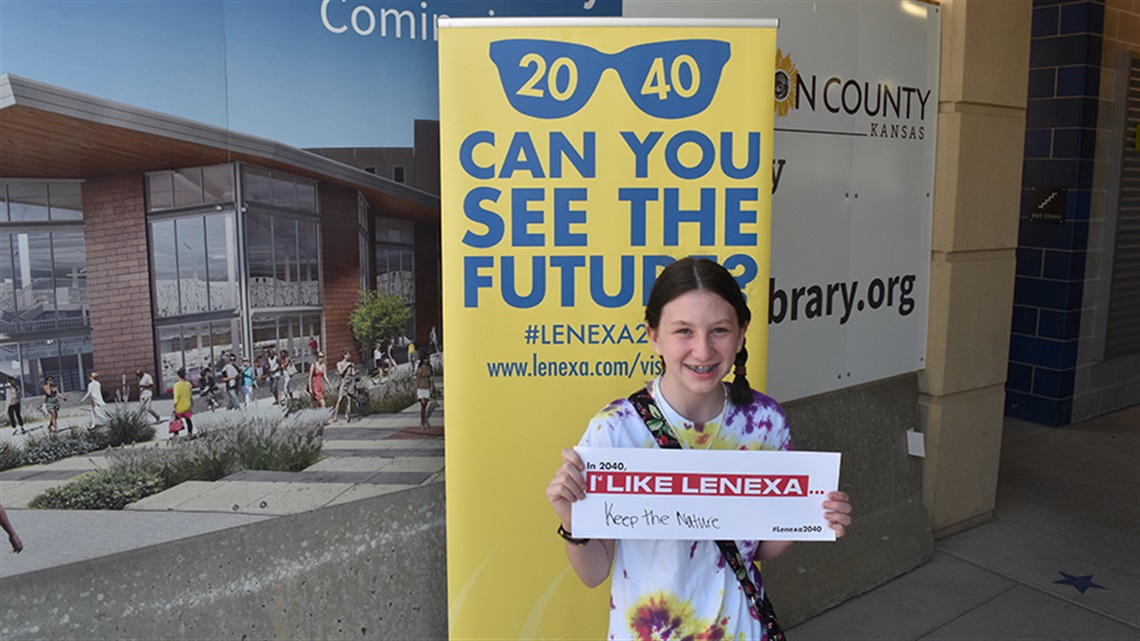 girl holding sign reading keep nature in front of Vision 2040 sign