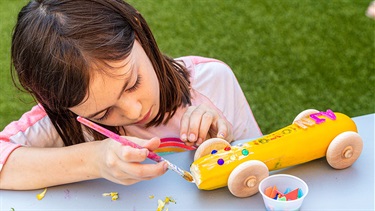 Girl decorates vegetable racecar