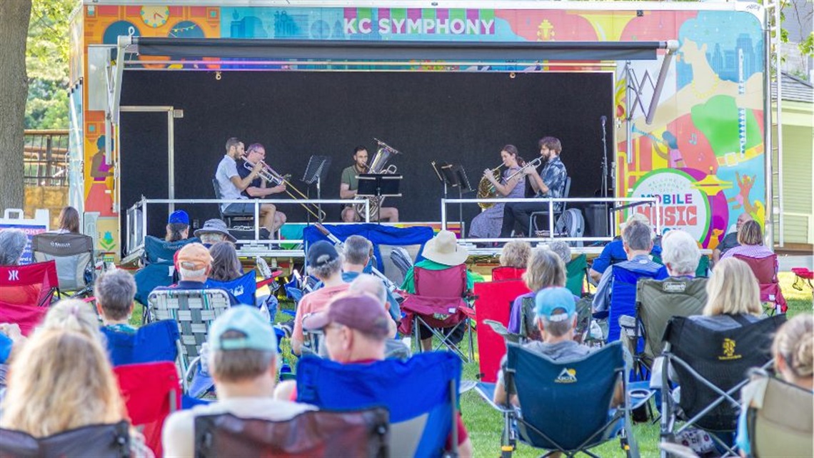 Musicians playing in KC Symphony Mobile Music Box while numerous others sit in lawn chairs outside