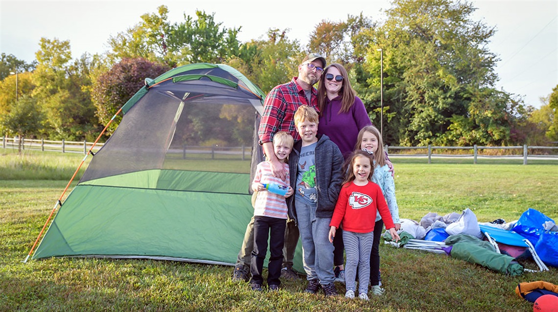 family standing next to tent in field