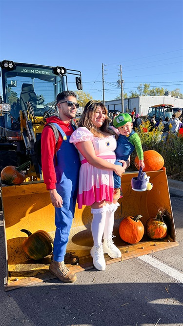 Family in costume poses near bulldozer