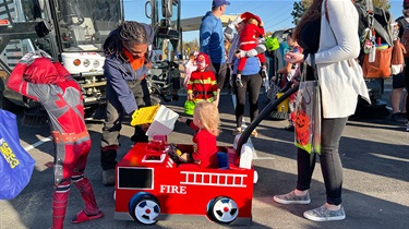 Child in fire truck wagon inspects candy offerings