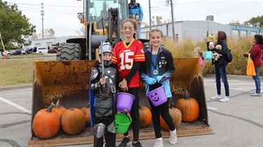 Kids in costume pose near bulldozer