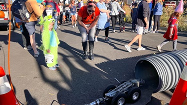 Boy and woman watch rover camera enter stormwater pipe