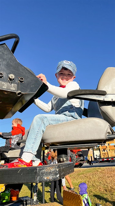 Kid dressed as train conductor sits on seat