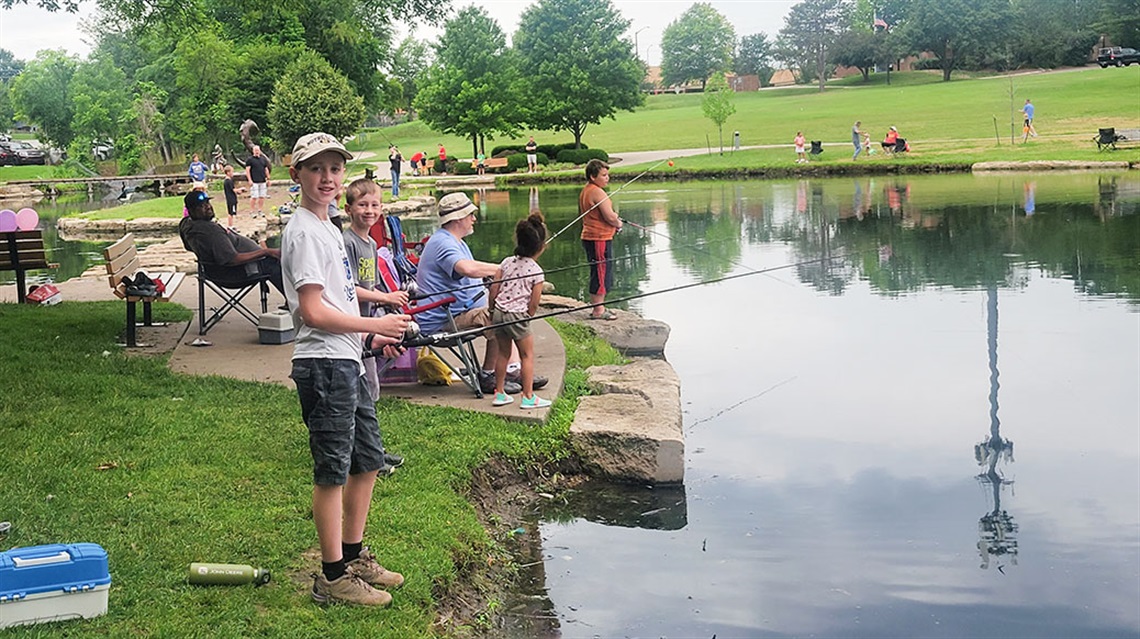 boy fishing at pond with other fishers in background