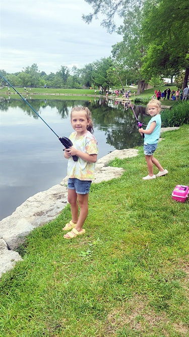 Two young girls fishing at pond