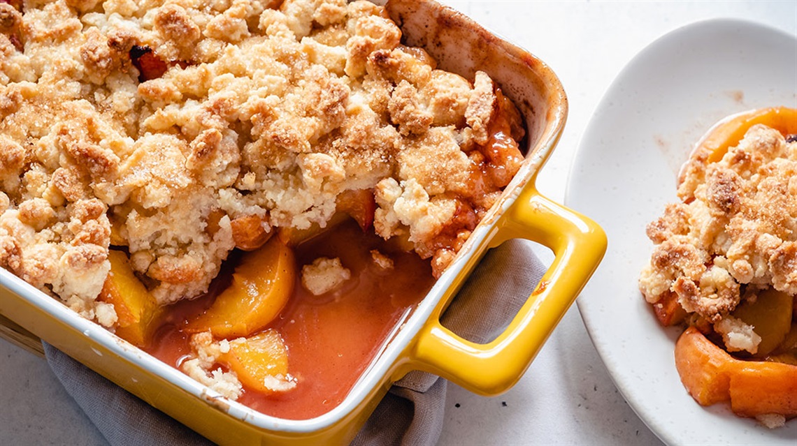peach cobbler in yellow baking dish with some served on a white plate