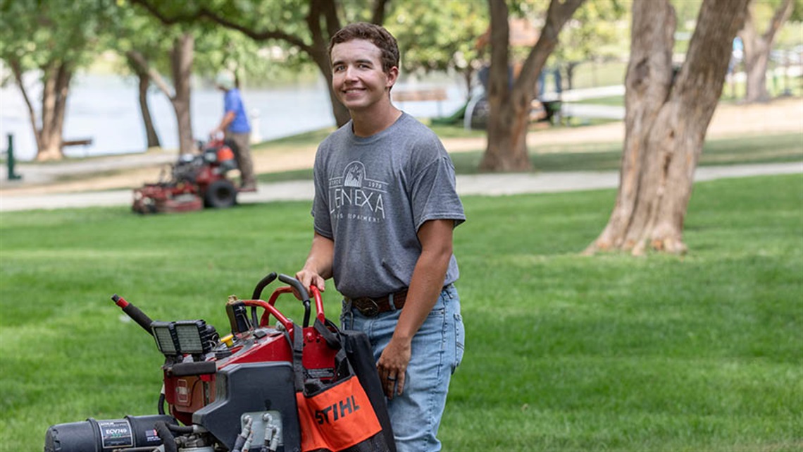 Employee in park with mowing equipment