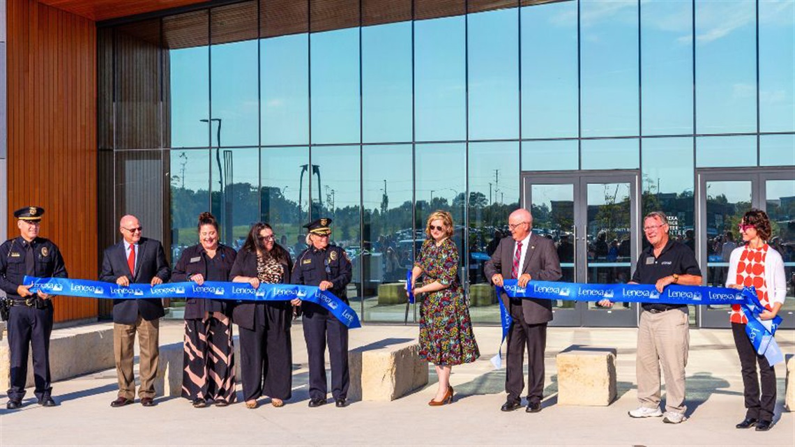 Group of people at ribbon-cutting for Lenexa Justice Center holding ribbon as Mayor Julie Sayers cuts it