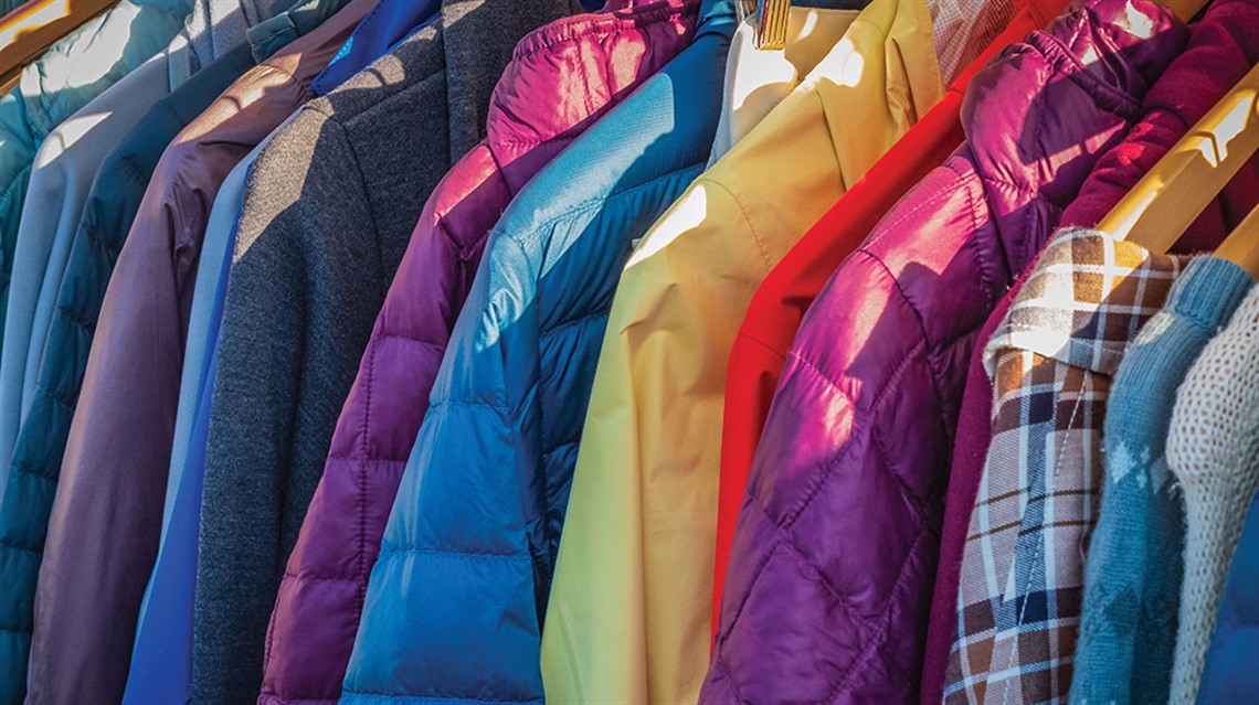 colorful array of coats on hangers in a row