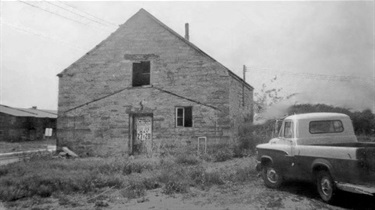 View of Legler Barn in 1950s at its original location with a truck in the foreground