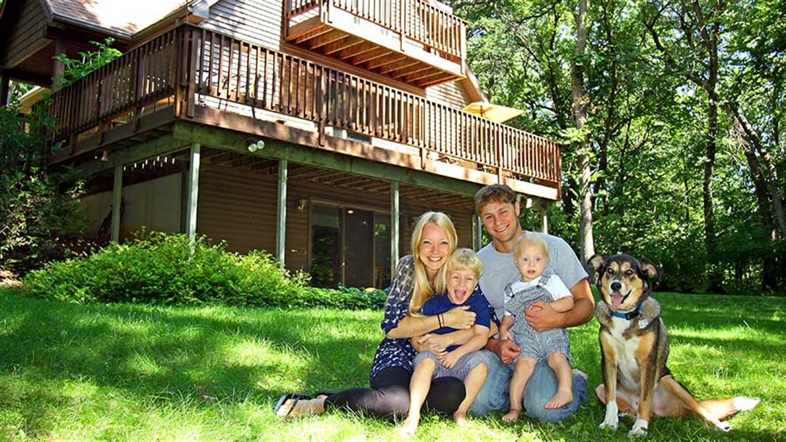 Family and dog in front of cabin