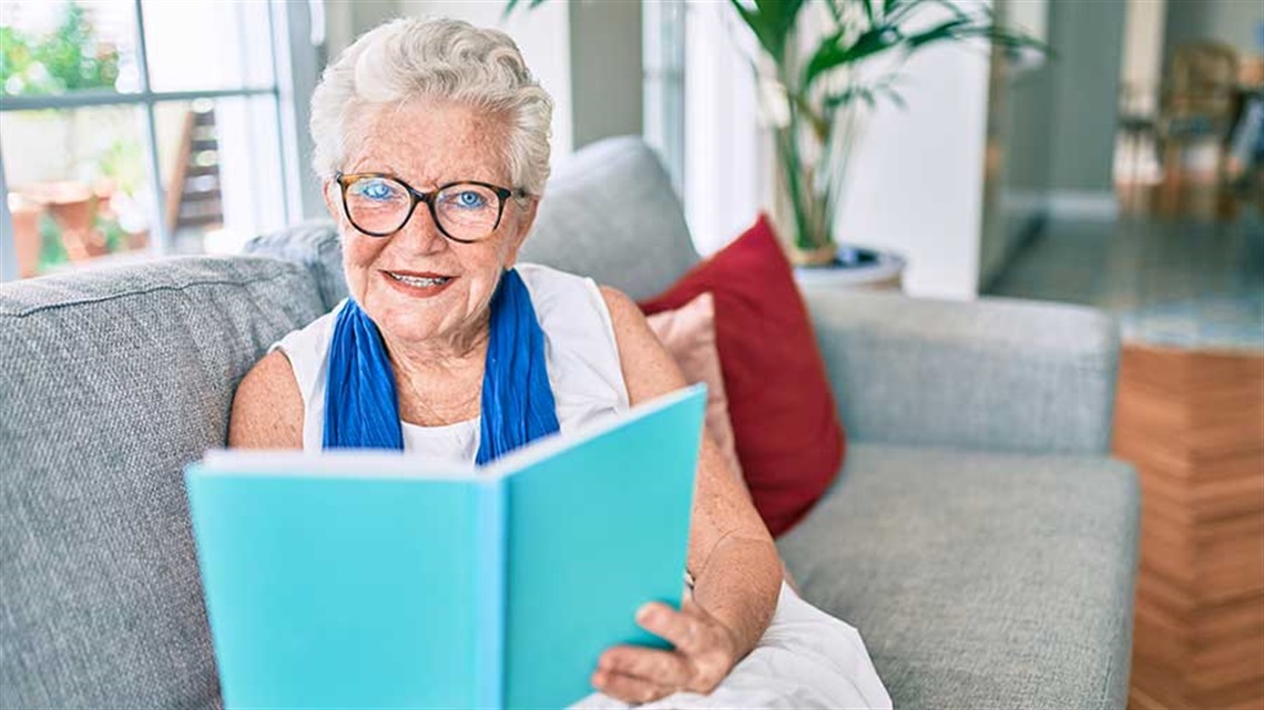Senior woman reading book on couch