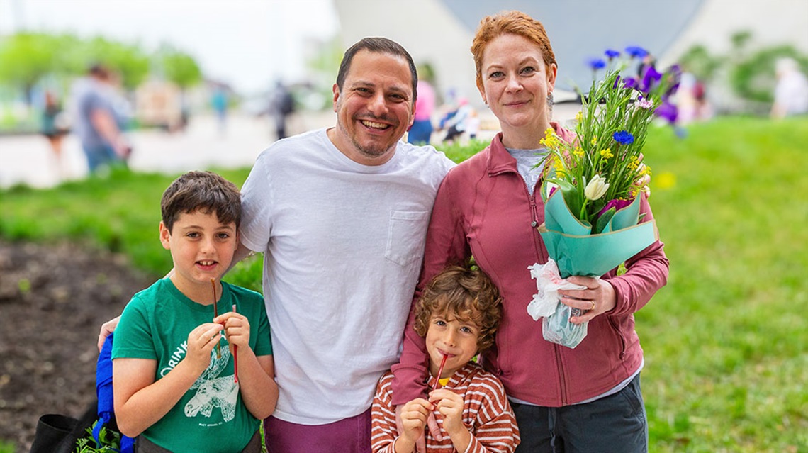 family of four pose with flowers and honey sticks